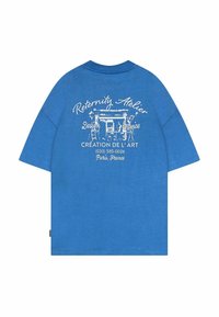 Sininen puuvillapaita, jossa on pyöreä kaula-aukko ja lyhyet hihat. Takana on valkoinen graafinen teksti ja kuva, mukaan lukien "Reternity Atelier" ja "Création de l'Art."