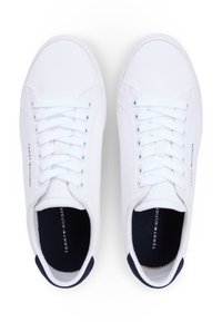 Λευκά πάνινα αθλητικά παπούτσια με χαμηλό κολάρο, στρογγυλή μύτη, επίπεδα κορδόνια και σκούρο μπλε λεπτομέρεια στη φτέρνα. Λογότυπο τυπωμένο στο εσωτερικό.