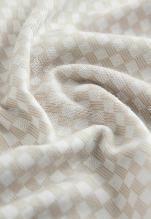 Țesătură împletită bej deschis cu un model în carouri; textură moale cu pliuri delicate și variații subtile de culoare și țesătură.