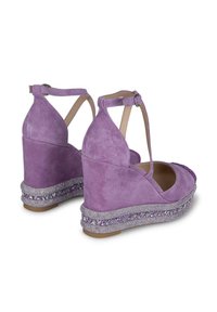 Chaussures compensées en suède violet avec une bride à la cheville et une plateforme ornée de bijoux. Les compensées présentent une texture lisse et un design à bout arrondi.