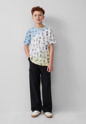T-shirt met korte mouwen in een vervagende kleurenschema van blauw naar geel, versierd met zwarte lijntekeningen van ijs en snacks. Gepaard met donkere cargobroeken.