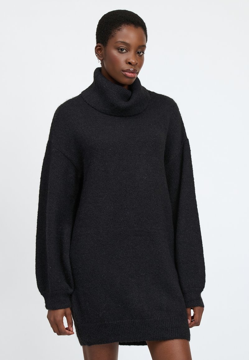 Schwarzes, übergroßes Strickkleid aus strukturiertem Maschenstoff, mit einem Rollkragen und langen, luftigen Ärmeln mit gerippten Manschetten.