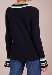 Námořnický žebrovaný svetr s límcem se zelenobílými pruhy a proužkovanými detaily na manžetách. Dlouhé rukávy, texturovaná pletenina.