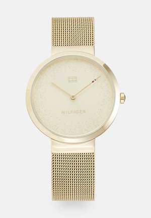 Gold-tone wristwatch with mesh band, minimalist dial, two hands, subtle speckled design, and "HILFIGER" branding beneath the 12 o'clock logo.