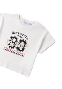 Camiseta blanca de manga corta con impresiones de texto en negro y rojo: "MEJOR ESTILO", "Universidad" y "REINA DE LA MODA"; escote redondo, tela suave.