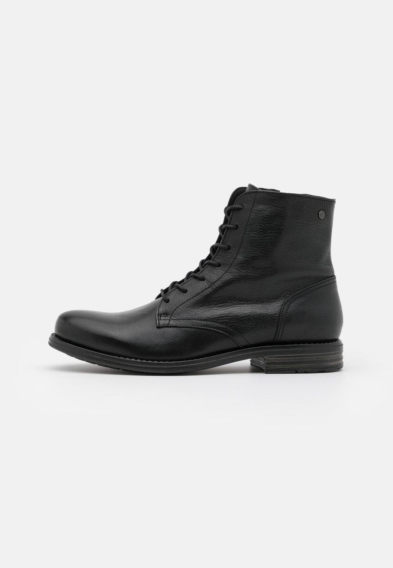 Botas de tobillo de cuero negro con puntera redondeada, diseño de cordones y superficie texturizada. Suela negra con un ligero detalle de tacón.