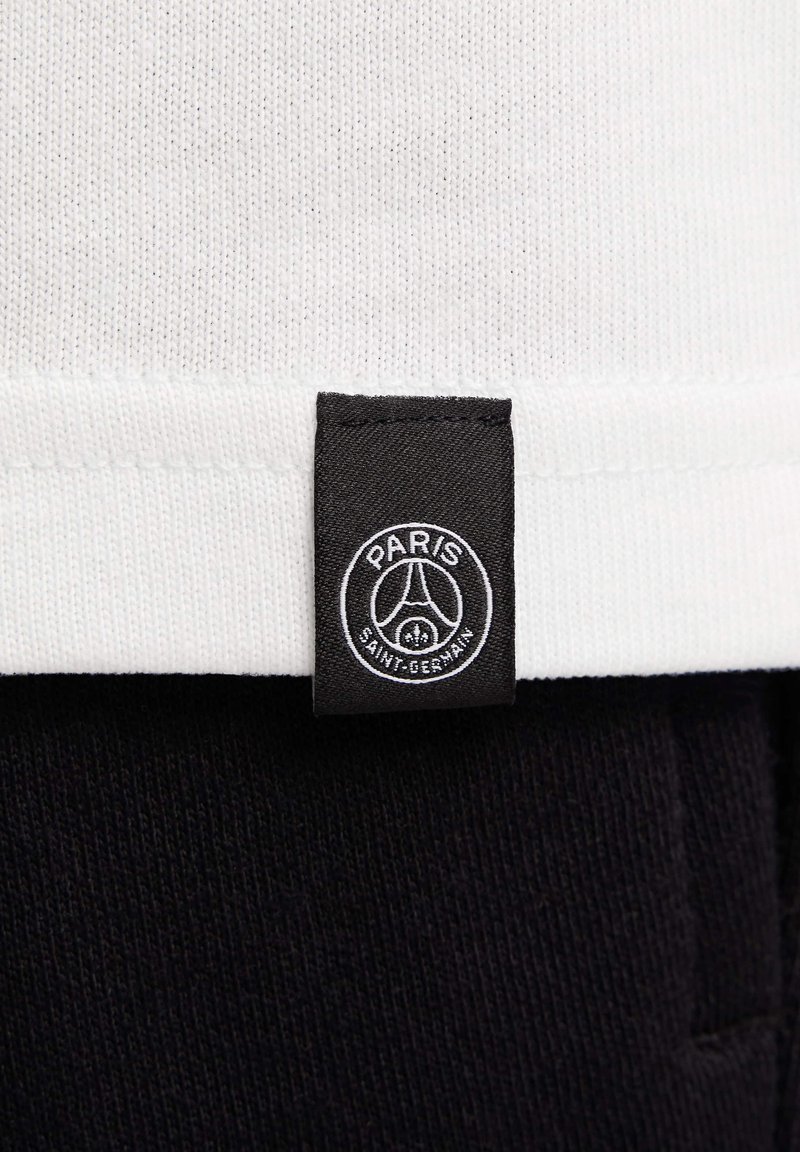 Biała tkanina o żebrowanej strukturze u góry, z czarną metką wyświetlającą logo z napisami "PARIS" i "SAINT-GERMAIN" w białym kolorze.