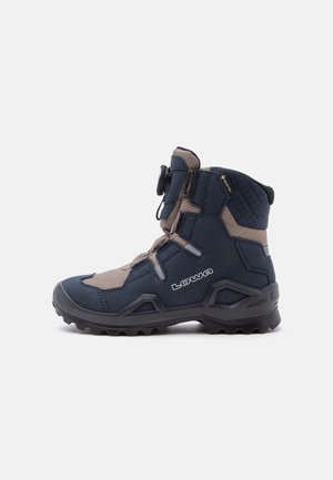 High-top hiking boot in blue and beige with rugged sole, adjustable dial closure, and Lowa and Gore-Tex branding on side.