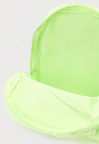 Ανοιχτό φουσκωτό πράσινο σακίδιο πλάτης που δείχνει άδειο κύριο διαμέρισμα και ανοικτό καπάκι σε λευκό φόντο.