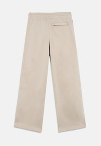 Beige Hose mit weitem Bein aus weichem Stoff, mit elastischem Bund und einer einzelnen Gesäßtasche zur Aufbewahrung.