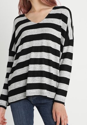 Zwart en grijs gestreepte blouse met lange mouwen, een V-hals, een comfortabele fit en een zachte textuur, gecombineerd met blauwe jeans.
