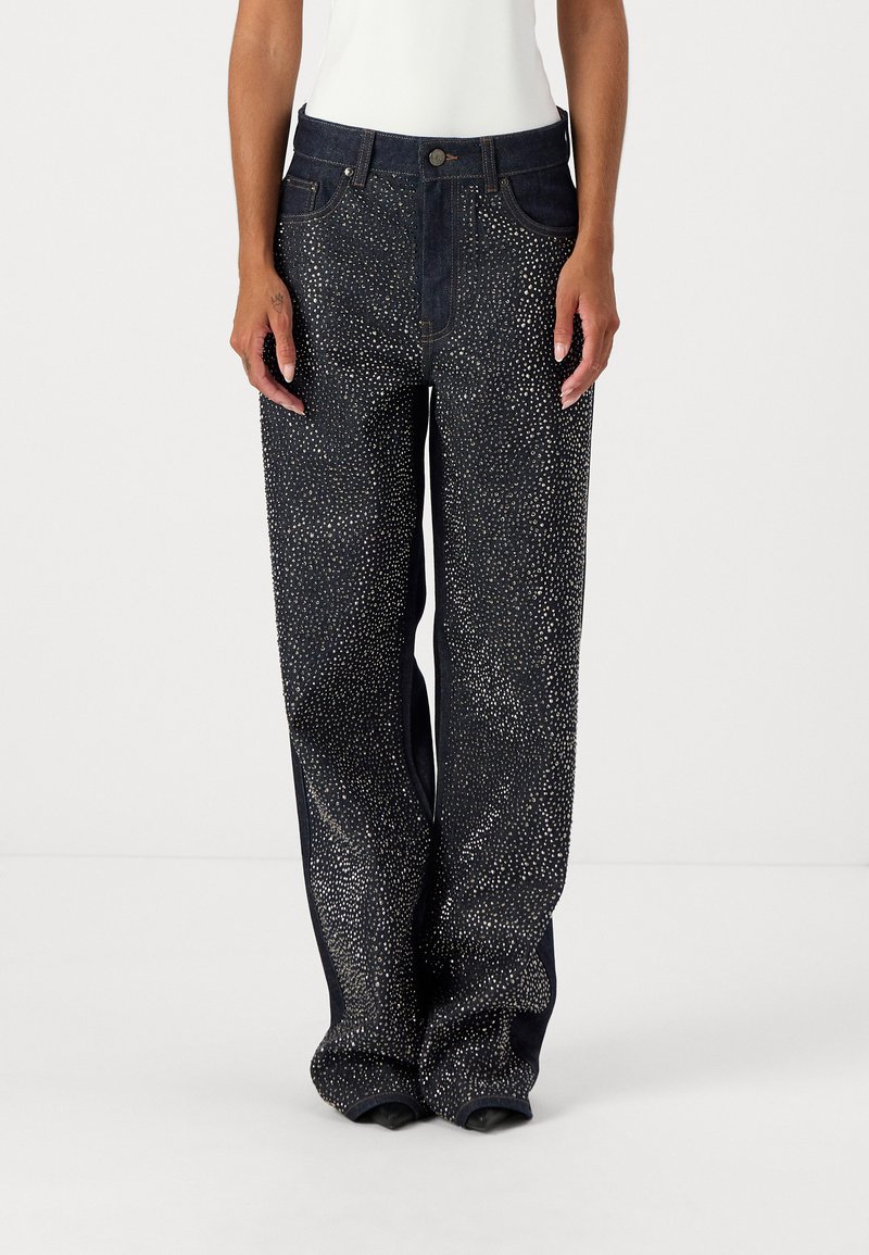 Jeans de pierna ancha de denim oscuro con embellishments metálicos, cinco bolsillos y cierre de botón. Textura suave con un ajuste holgado.