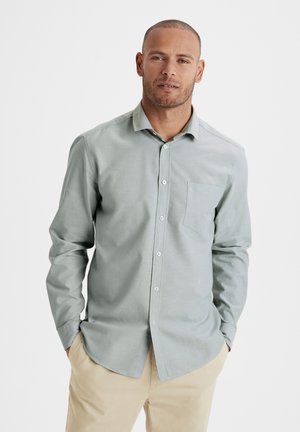 Camicia a maniche lunghe verde chiaro con bottoni, dotata di taschino sul petto, realizzata in tessuto con texture liscia e lucentezza sottile; orlo arrotondato.