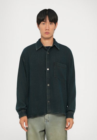 Chemise en denim foncé avec un devant à boutons, un col et des manches longues. Présente une poche poitrine unique et une coupe décontractée.