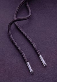 Cordon en tissu torsadé de sweat-shirt violet avec embouts en plastique transparent arborant un logo. Fond de tissu lisse.