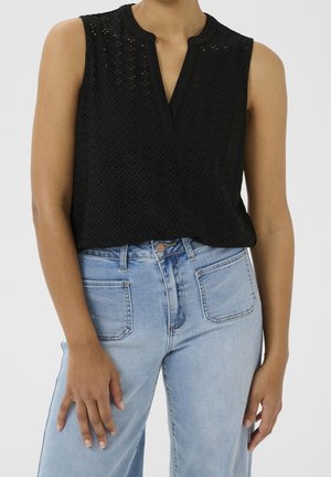 Black sleeveless top with a textured diamond pattern and a v-neck line, paired with light blue high-waisted jeans featuring rear pockets.
