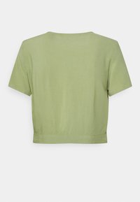 Top accorciato a maniche corte in morbido tessuto verde chiaro con una texture liscia e scollatura rotonda. L'orlo è dritto e senza decorazioni.