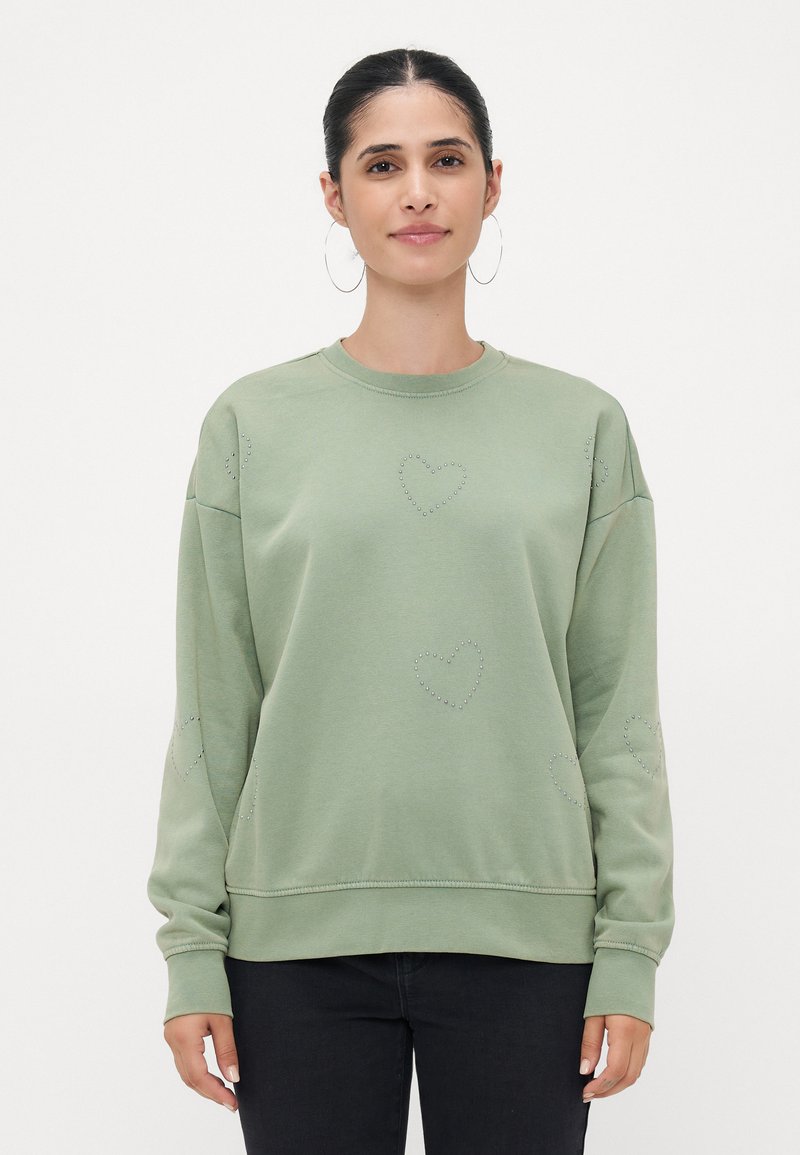 Svetlozeleni pulover iz mehkega blaga, z akcenti v obliki srčkov na sprednjem delu in rokavih, sproščenega kroja ter rebrastimi manšetami.