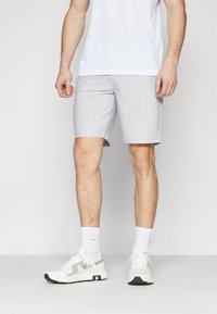 Lys grå shorts med en glatt tekstur, knelengde, kombinert med hvite joggesko og trening sokker. Enkel, funksjonell design.