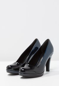 Tacchi alti in vernice nera con punta arrotondata, finitura lucida e sottile tacco a stiletto. Texture liscia, design minimalista.