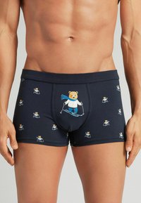 Námořnické modré pánské boxerky vyrobené z měkké látky, s designem lyžujícího medvěda a menšími vzory medvědů po celém povrchu.
