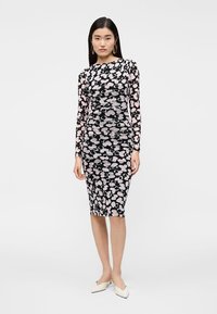 Vestido de manga comprida, justo, feito de tecido elástico, com base preta e padrões florais abstratos em rosa e branco. Design de comprimento midi.