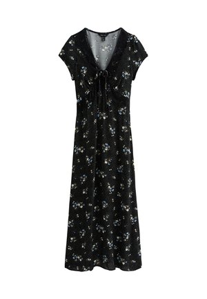 Robe noire à fleurs avec des manches courtes, un col en V, un détail à nouer à la taille, et une jupe fluide jusqu'aux chevilles avec un motif à pois.