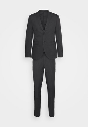 Mörkgrå kostym med en enfärgad kavaj och avsmalnande byxor. Har två knappar, en bröstficka och en slät tygstruktur.