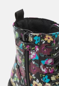 Bota de tobillo floral con estampado negro, material sintético texturizado, cierre de cordones y cremallera, y tira en la parte superior.