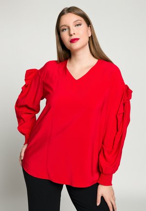 Blusa rossa con scollo a V, dotata di maniche a palloncino con dettagli arricciati. Realizzata in un tessuto morbido, progettata con una vestibilità comoda.