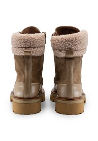 Stivaletti in camoscio marrone con un morbido risvolto in shearling rosa, dettagli in pelle liscia, chiusura con cerniera e una robusta suola beige.