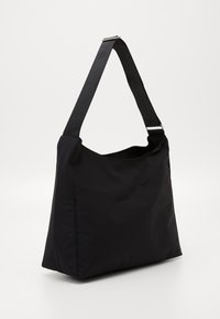 Schwarze Stofftragetasche mit breitem Korpus, flachem Boden und langem, verstellbarem Tragegurt. Glatte Textur und minimalistisches Design mit silbernen Hardware-Akzenten.
