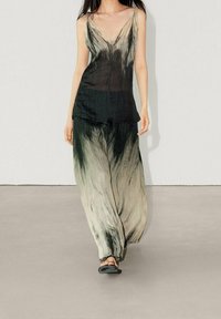 Un haut v-neck fluide noir et crème accompagné de pantalons large assortis, en tissu léger avec un motif tie-dye fluide.