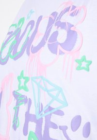 Kortærmet hvid t-shirt med farverige grafiske designs i pastel pink, grøn og lilla, herunder stjerner og en diamantform.