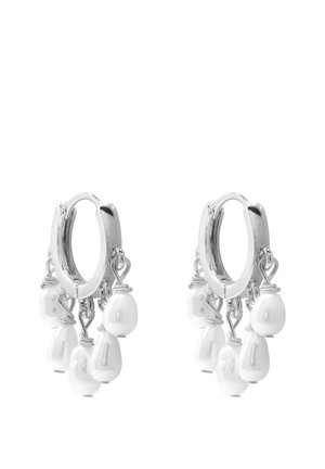 Srebrne kolczyki-koła z wieloma zawieszonymi białymi perłami o nieregularnych kształtach, przymocowanymi małymi kółeczkami.