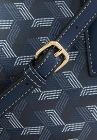 Navy blue handbag featuring a geometric hexagonal pattern in white and light blue, with a gold metal buckle and contrasting cream stitching.