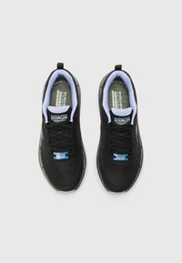 Scarpe sportive nere con tomaia in mesh traspirante, lacci e suole morbide. Presentano una fodera di colore chiaro e un marchio sulla linguetta.