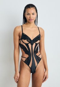 Must mustriba musta pitsiline bodysuit, millel on vormitud tassid, lõigatud sektsioonid, õhukesed rihmad ja lillepitsist aktsendid, mis rõhutavad selle keerukat disaini.