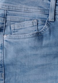 Jeans in denim blu chiaro con tasca frontale, cuciture visibili e un piccolo bottone metallico decorativo. Texture liscia con una finitura scolorita.