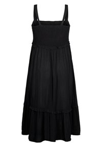 Vestido negro con un cuerpo fruncido, tirantes finos y una falda acampanada y con volantes. Hecho de una tela ligera con una textura suave. Detalle de dobladillo con volantes.
