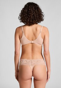 Beige bh en string set, met een soepele stof en bloemenkant accenten op de tailleband van de string. Verstelbare bandjes met een haaksluiting.