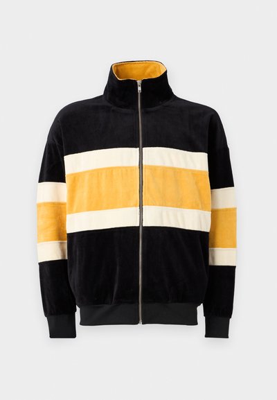 Fleece-Zip-Jacke mit hohem Kragen, ausgestattet mit horizontalen Streifen in Schwarz, Gelb und Creme sowie gerippten Bündchen und Saum.