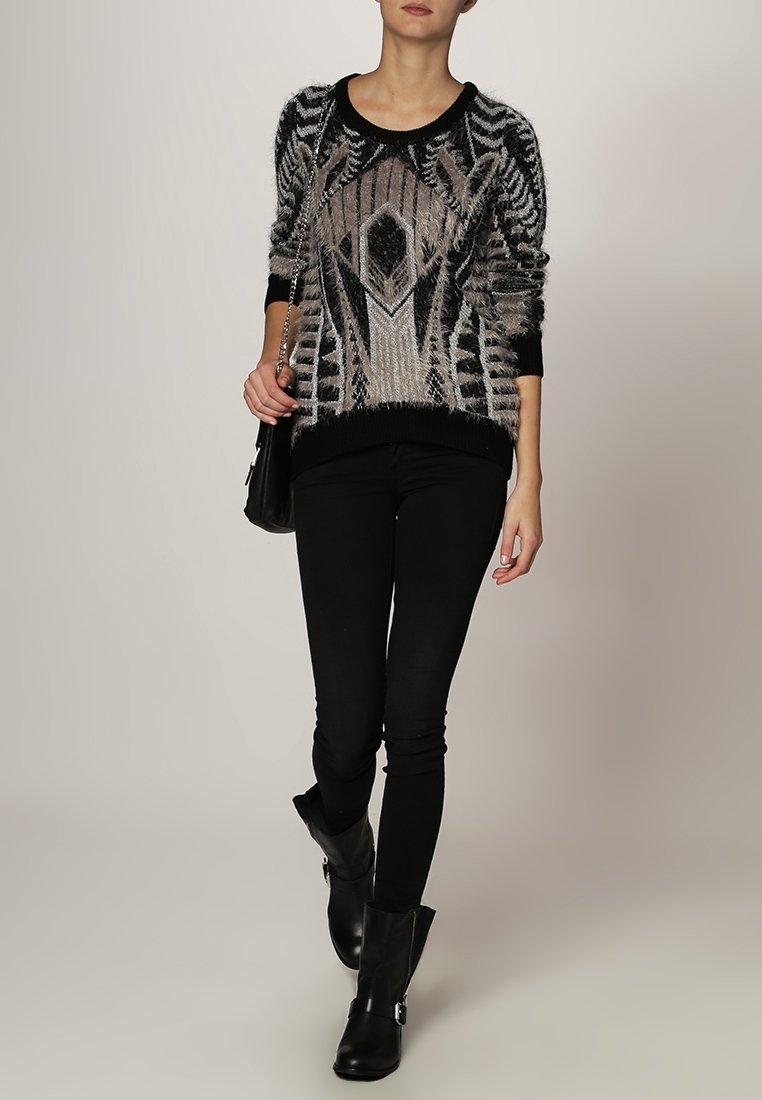 Maglione a righe nero e grigio con texture pelosa, abbinato a jeans skinny neri e stivaletti, con una borsa a tracolla con catena.