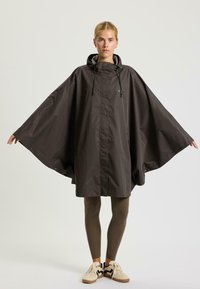 Poncho impermeabile di colore grigio scuro con cappuccio, bottoni a pressione e dettagli con cordino; presenta maniche ampie e tasche frontali.