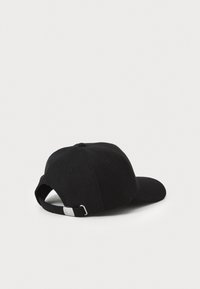 Svart caps med strukturert design, myk stoff, buet brem, justerbar stropp bak, og en liten sølv detalj.