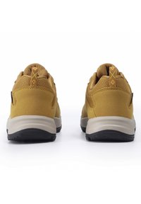 Zapatillas de malla amarilla y ante con suela de goma negra. Incluyen una lengüeta con un diseño de diamante y un collar acolchado para mayor comodidad.