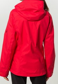 Veste imperméable rouge avec capuche, présentant une texture lisse et des manches longues. Comprend un petit logo sur le bras gauche.
