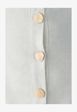 Beiger Leinenstoff mit drei dekorativen, muschelförmigen Knöpfen mit detaillierten Strukturen, die vertikal entlang der Kante verlaufen.