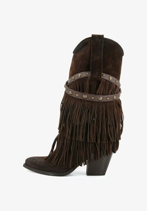 Stivale da cowboy in suede marrone scuro con tacco impilato, frangia a strati e cinturino in pelle con borchie intorno alla caviglia.
