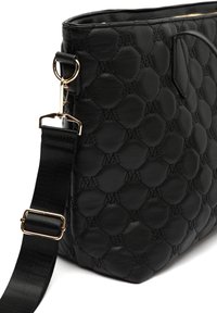 Sac en cuir noir avec un motif capitonné hexagonal, doté d'un accent en matériel doré et d'une bandoulière noire amovible. Texture lisse.